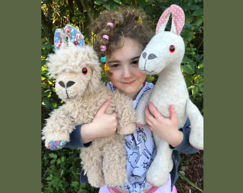 Handmade plush llama and bunny stuffed animals, girl holding soft toys, eco-friendly handmade toys, Threadistry craft dolls.