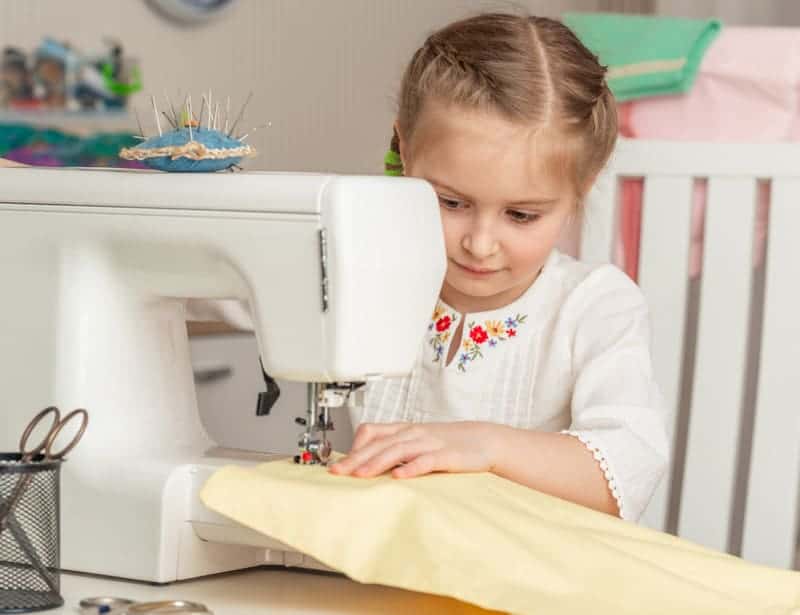 Little girl sewing on a sewing machine
