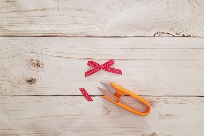 Scissors trimming the tail of a perfect ribbon bow