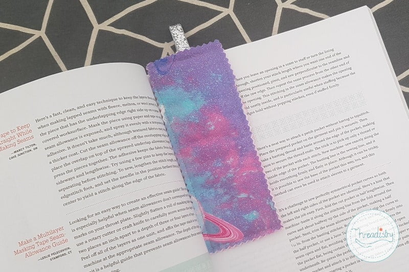 Purple, pink and blue fabric bookmark resting on an open book