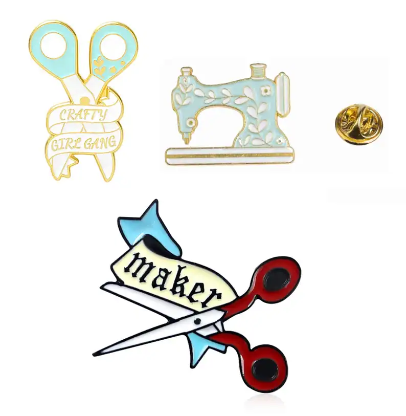 Colorful sewing-themed enamel pins with scissors, sewing machine, and motivational phrases.