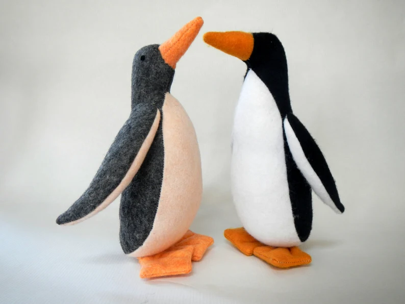 Two realistic felt penguins with their wings out