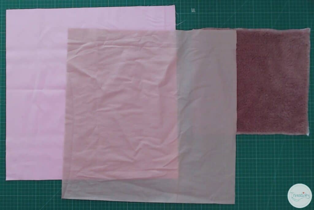 Cut out squares of pink fabric on a cutting table
