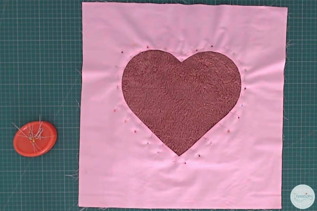 Pink fabric with heart cutout, with fluffy dark pink fabric pinned underneath the cutout