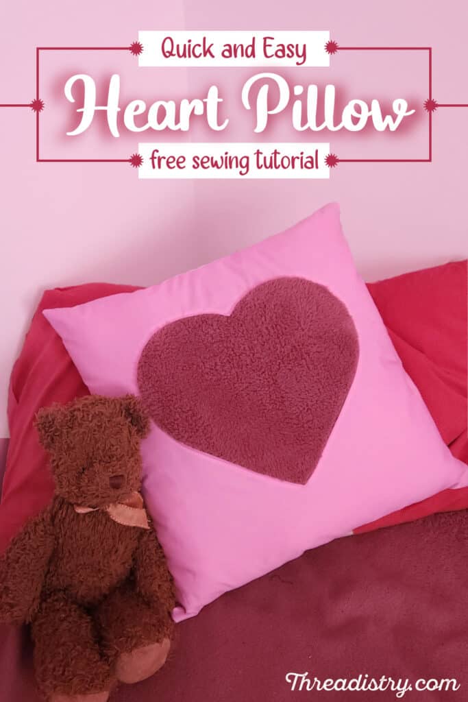 Square pillow with heart applique lying on a bed with a teddy bear with text overlay "Quick and Easy Heart Pillow free sewing tutorial"