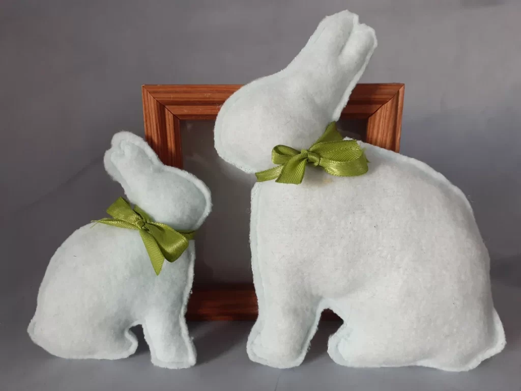 Two simple white Easter bunny plush toys with green ribbons around their necks.
