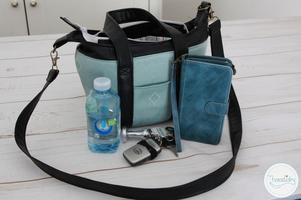 Mint and black Lily handbag with phone keys and small water bottle next to it to show size.