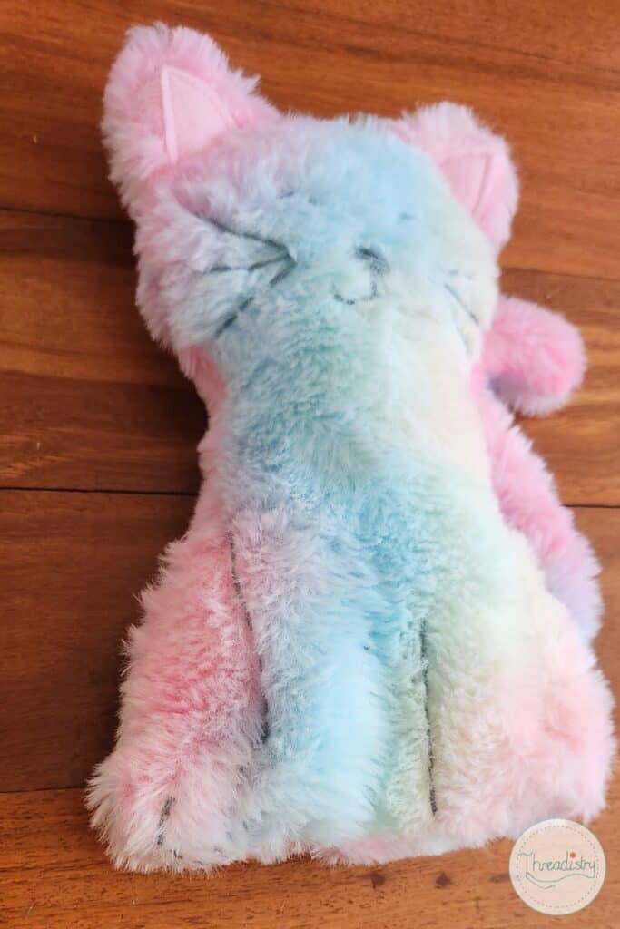 Soft pastel pink and blue plush cat-shaped pillow, perfect for cozy home decor or gifts.