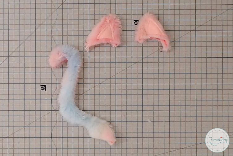 Fluffy pink and white plush craft materials on graph paper for DIY stuffed animal creation.