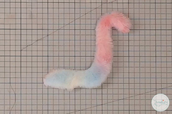 Colorful plush thread art in pastel shades on grid background, creative handmade textile craft.