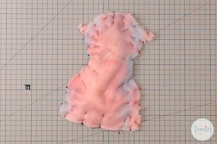 Soft pink plush fabric with messy, loose stitches for sewing or craft projects.