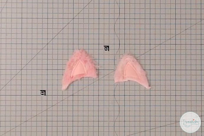 White fluffy pink angel wing embroidered patches on graph paper.