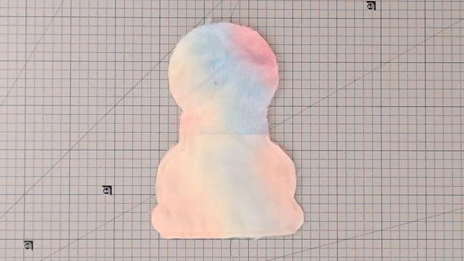 Colorful yarn offcut shaped like a paw print on grid paper background for craft projects.