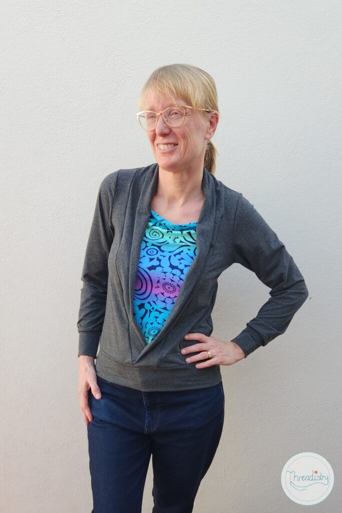 Warm professional woman with glasses and a colorful shirt, standing confidently against a plain background.