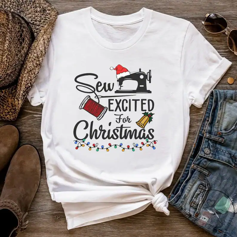 Festive Christmas sewing shirt with Santa hat, thread, bell, holiday lights design.