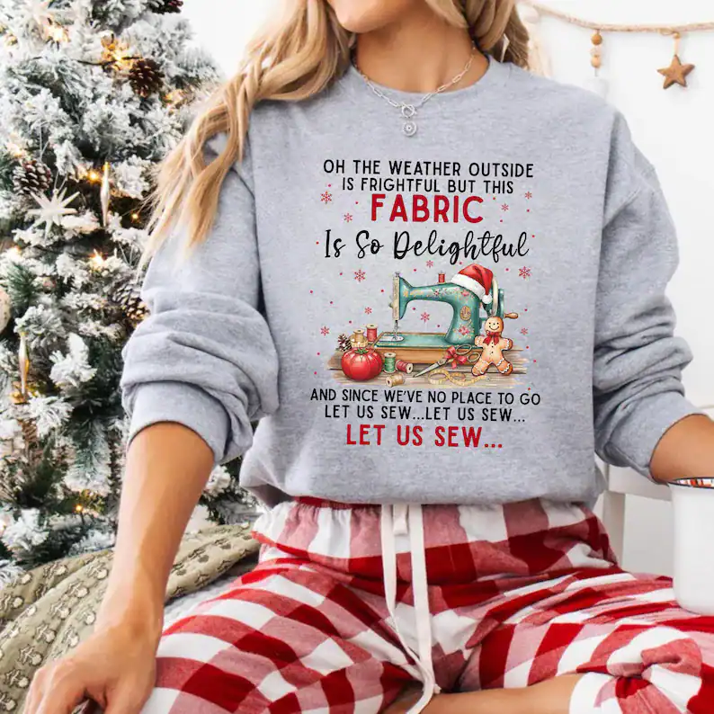 Festive Christmas sweatshirt with sewing-themed design and holiday quote, perfect for cozy winter celebrations.
