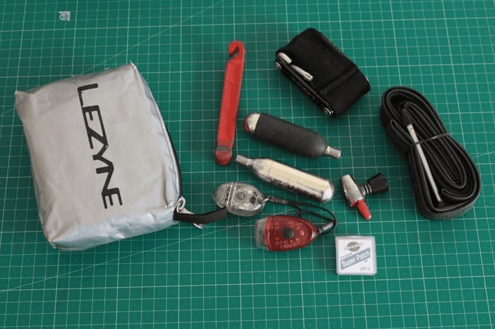 Adjustable bicycle pump with tools and accessories on green cutting mat for cycling repairs and maintenance.