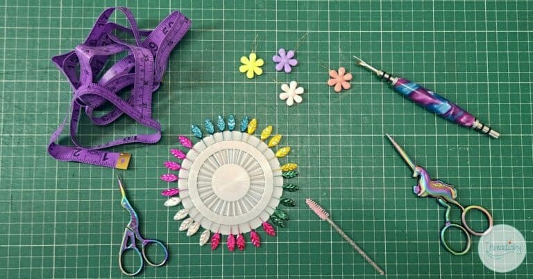 Sewing tools including scissors, pins, and measuring tape on a green cutting mat.