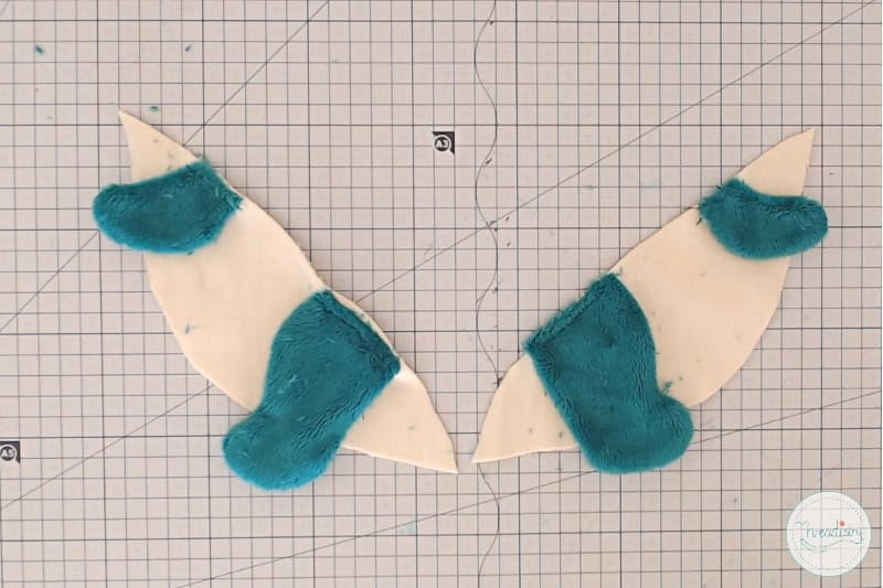 Fabric and plush material sewing project with cut-out fabric pieces and fuzzy patches.