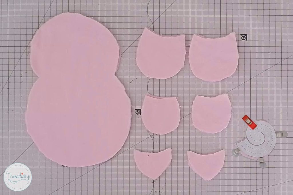 Pink fabric cutouts for crafting, including a large snowman shape and smaller pieces.