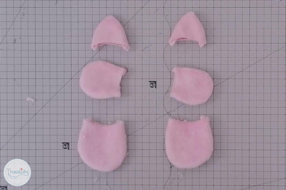 Pink fabric pieces cut into piggy shape for craft project.