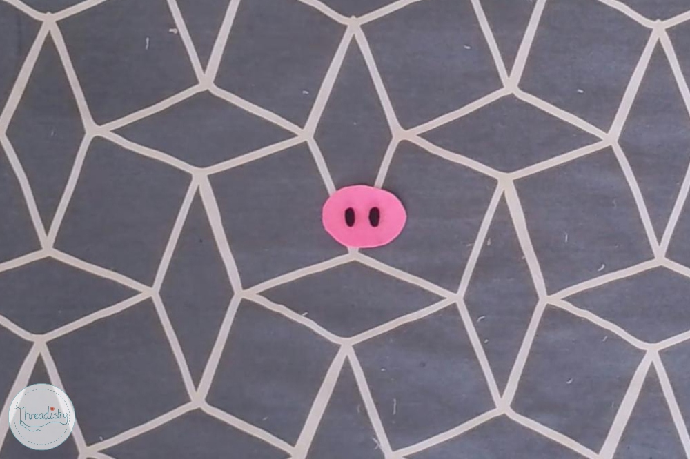 Pink pig face on a geometric patterned background.