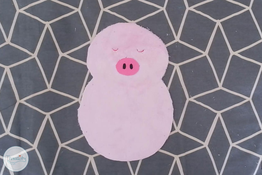 Cute pink pig plush toy on geometric patterned background.