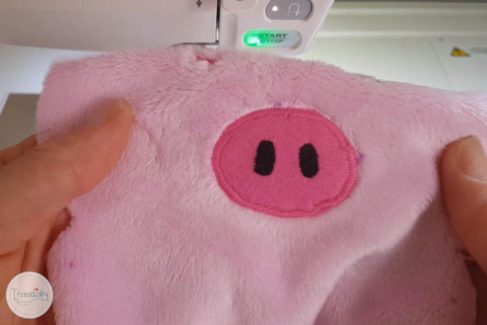 Close-up of a pink plush piggy bank with a digital coin counter in the background.